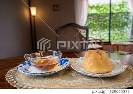 カフェのテーブル席で食べるシュークリームと紅茶 129653575
