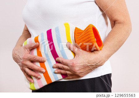 Senior woman with hot water bottle on her stomach. Help with pain in old age 129655563