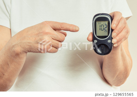 Senior woman and glucometer with result of sugar level. Diabetes in old age 129655565