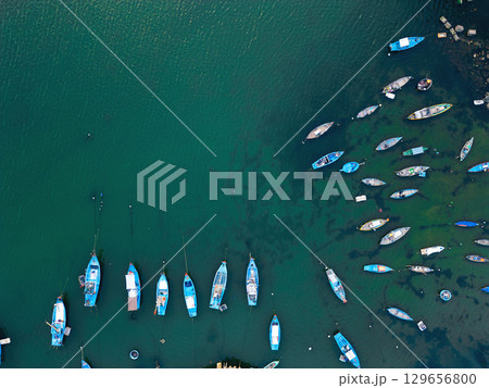 aerial view of fishing boats in blue water, serene harbor and peaceful marine tranquility, drone perspective of anchored vessels on turquoise sea, calm bay and nautical harmony 129656800