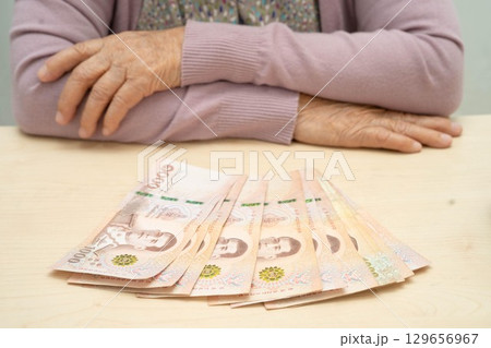 Retired Asian elderly woman counting coins money and worry about monthly expenses and treatment fee payment. 129656967