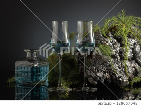 Blue gin on a black reflective background. 129657048