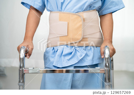 Asian senior pain back wearing elastic support belt with walker. Asian senior pain back wearing elastic support belt with walker. 129657269