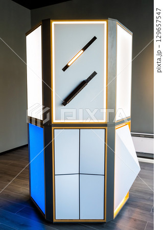 Illuminated display stand in a stretch ceiling and lighting store, showcasing built-in LED light fixtures and modern panel designs. Illuminated display stand in a stretch ceiling and lighting store, showcasing built-in LED light fixtures and modern panel designs. 129657547