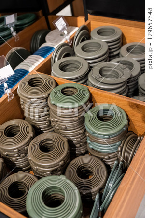 Stacks of round plastic trim rings for stretch ceiling installation, used to secure and finish openings for recessed lighting fixtures. 129657548