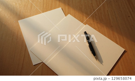 Three sheets of paper are stacked on top of each other with a pen on top of the 129658074