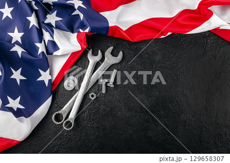 Wrenches and bolts with American flag on black background symbolizing U.S. Labor Day. top view. copy space 129658307