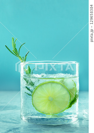 Gin tonic glass, side view with rosemary and lime. Fresh summer cocktail Gin tonic glass, side view with rosemary and lime. Fresh summer cocktail 129658384