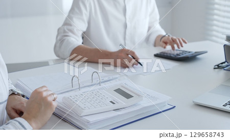 Close up of a calculator on financial documents, with an accountant hands working with, finance, and tax preparation. Audit and taxes in business Close up of a calculator on financial documents, with an accountant hands working with, finance, and tax preparation. Audit and taxes in business 129658743