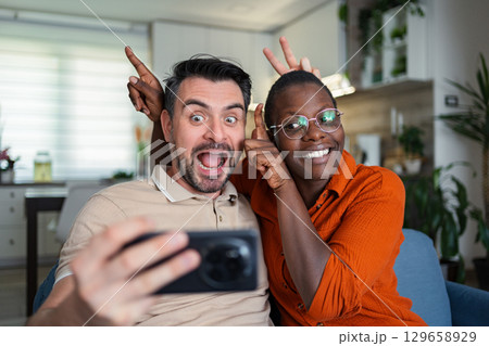 Playful couple taking a selfie making funny faces at home 129658929