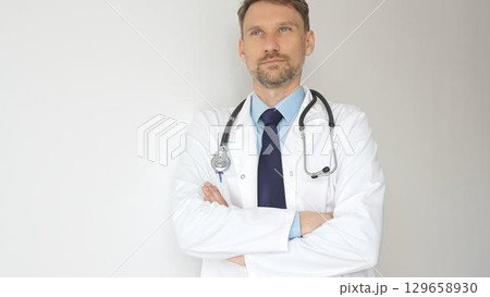Headshot of a confident doctor man wearing stethoscope and white coat, is standing with crossed arms, representing medical professionalism and expertise. Medicine and health care 129658930