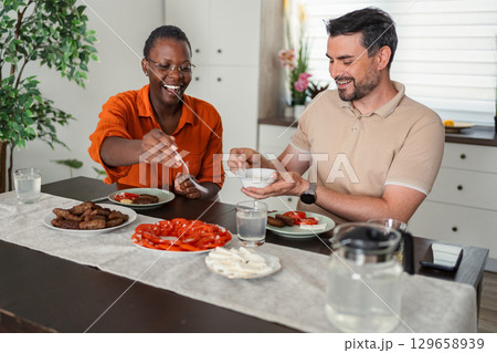 Happy couple enjoying a healthy meal together at home Happy couple enjoying a healthy meal together at home 129658939