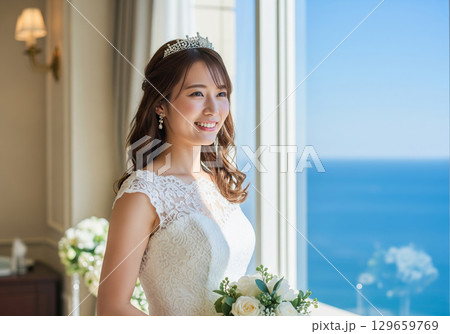 ホテルから海を眺めるティアラをつけたウェディングドレス姿の女性 129659769