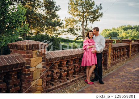 Man gently hugging pregnant woman while sitting in garden at home.  129659801