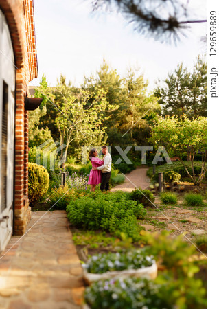 Man gently hugging pregnant woman while sitting in garden at home.  129659889