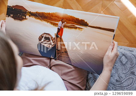 woman is holding and flipping through a photo book with a pregnancy photo shoot 129659899