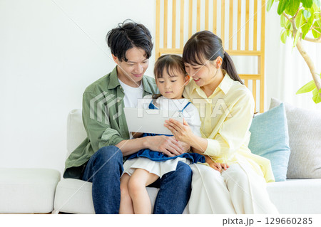 リビングでタブレットを見る若い家族 129660285