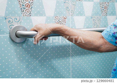 Asian elderly woman use safety handrail in bathroom. 129660481