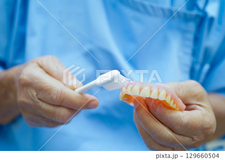Doctor clean teeth denture with toothbrush for teach patient and dentist studying about dentistry. Doctor clean teeth denture with toothbrush for teach patient and dentist studying about dentistry. 129660504