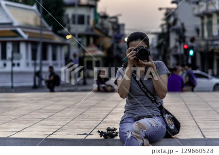 A Woman siting down on the floor and takes pictures with a camera at The Giant Swing (Sao Ching Cha). A Woman siting down on the floor and takes pictures with a camera at The Giant Swing (Sao Ching Cha). 129660528