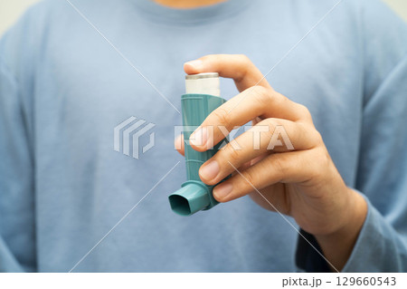 Asthma and chronic obstructive pulmonary disease COPD, Asian young man using metered dose inhaler MDI. Asthma and chronic obstructive pulmonary disease COPD, Asian young man using metered dose inhaler MDI. 129660543