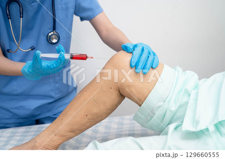Doctor checking Asian elderly woman patient with scar knee replacement surgery in hospital. 129660555