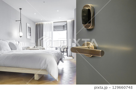 Opened door of hotel room with bedroom background 129660748