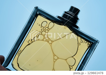 A bottle of perfume with a spray gun on a blue background with an illuminated texture. 129661478