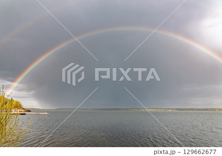 Rainbow over Blue lake with cloudy sky 129662677