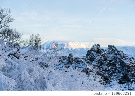 夕陽に染まる雪景色のディムボルギル溶岩地形と山並み（アイスランド） 129663251