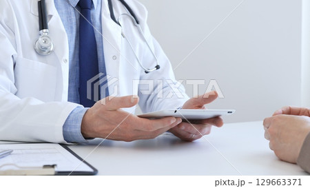 Close-up of doctor man showing information on tablet to patient woman during medical visit, explaining diagnosis and treatment options, providing medical consultation. Medicine concept 129663371