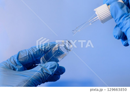 Preparing a solution using a dropper and vial in a laboratory setting with a focus on precision and safety 129663850