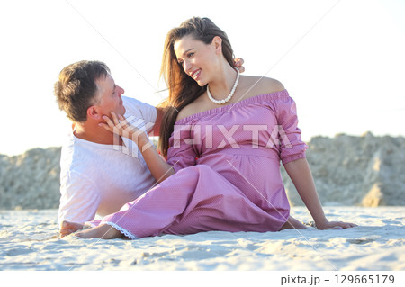 Couple enjoying a romantic moment on the beach during sunset in warm weather Couple enjoying a romantic moment on the beach during sunset in warm weather 129665179