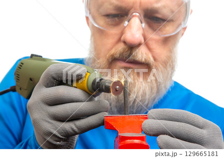 Craftsman performing detailed work with rotary tool on metal in workshop Craftsman performing detailed work with rotary tool on metal in workshop 129665181