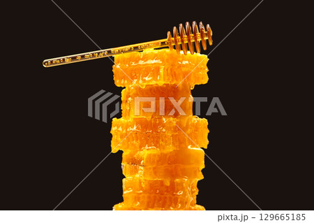 Delicious honeycomb stacked with a honey dipper resting on top 129665185