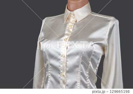 Elegant silk blouse showcased on a mannequin against a grey backdrop for fashion display 129665198