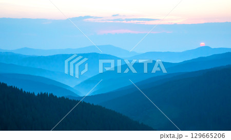 Sunset over misty mountain ranges showcasing serene landscapes and natural beauty 129665206