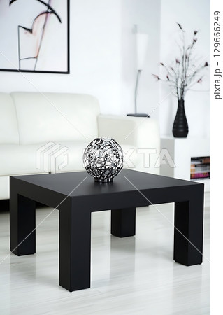 A black coffee table with a white vase on top of it 129666249