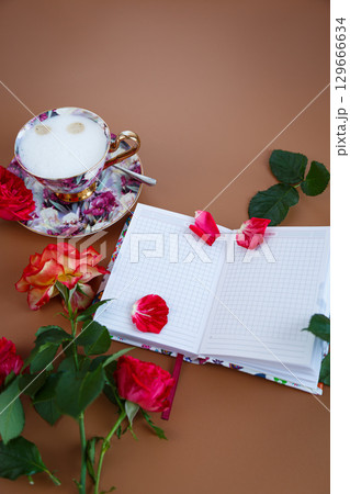 An open diary with rose petals and a fragrant drink An open diary with rose petals and a fragrant drink 129666634