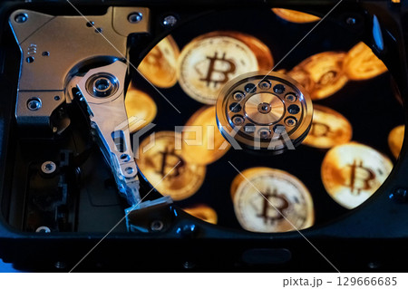 An open hard drive with reflections of gold Bitcoin coins on its surface An open hard drive with reflections of gold Bitcoin coins on its surface 129666685