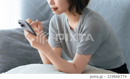 ソファに座ってスマートフォンを使う女性 ソファに座ってスマートフォンを使う女性 129666774