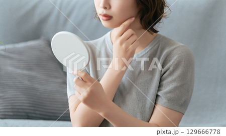 鏡で肌をチェックする女性 129666778