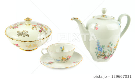 Elegant vintage porcelain coffee pot, vintage sugar bowl, porcelain cup and saucers isolated on white. Collage. Elegant vintage porcelain coffee pot, vintage sugar bowl, porcelain cup and saucers isolated on white. Collage. 129667031