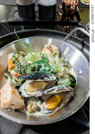 Hot pan with seafood. Mussels, squid, shrimp, salmon, zucchini in creamy sauce Hot pan with seafood. Mussels, squid, shrimp, salmon, zucchini in creamy sauce 129667047