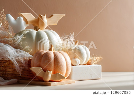 A beautiful Halloween display features elegant pumpkins, playful bats, and a white ghost arranged with delicate spiderwebs for autumn. 129667086