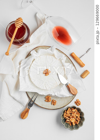 Fresh brie cheese with walnuts and honey, served with wine on white table. Top view Fresh brie cheese with walnuts and honey, served with wine on white table. Top view 129669000
