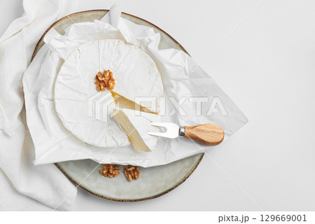 Cutted fresh brie cheese with walnuts on white table. Top view 129669001