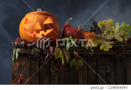 Halloween pumpkin head jack lantern with dried-up leaves. 129669045