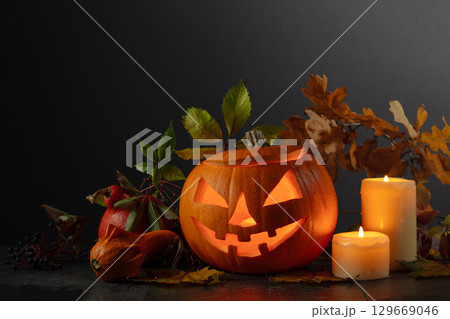 Halloween pumpkin head jack lantern with dried-up leaves. 129669046