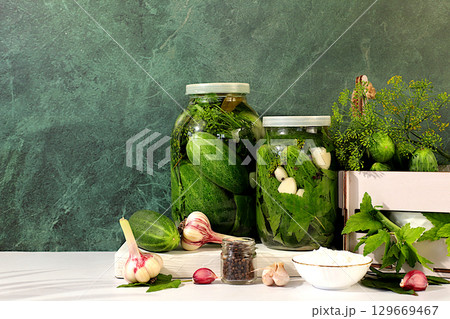 Pickled cucumbers in a jar with garlic and dill on the kitchen table, village harvest, homemade pickling recipe, cucumbers and ingredients for pickling, home canning concept, healthy and natural food. Pickled cucumbers in a jar with garlic and dill on the kitchen table, village harvest, homemade pickling recipe, cucumbers and ingredients for pickling, home canning concept, healthy and natural food. 129669467